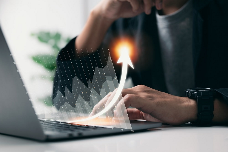 Close-up of hands pointing at a laptop screen displaying a glowing upward trend, symbolizing a surge in enterprise SEO success.