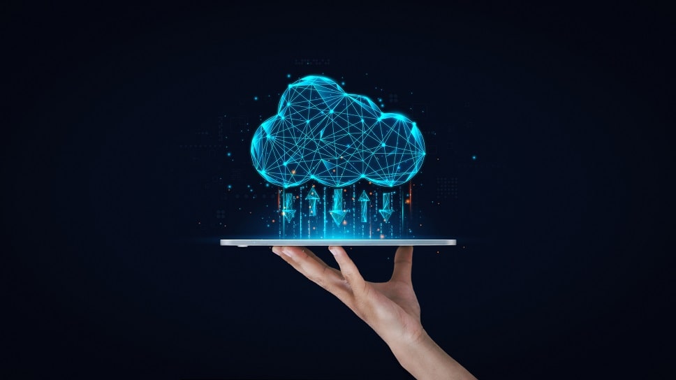Hand holding a tablet displaying a 3D cloud computing network concept with digital connections and city skyline hologram.