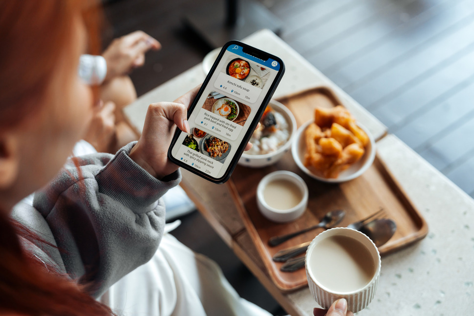 Person using phone to order food online in a restaurant, representing business success with food website development services