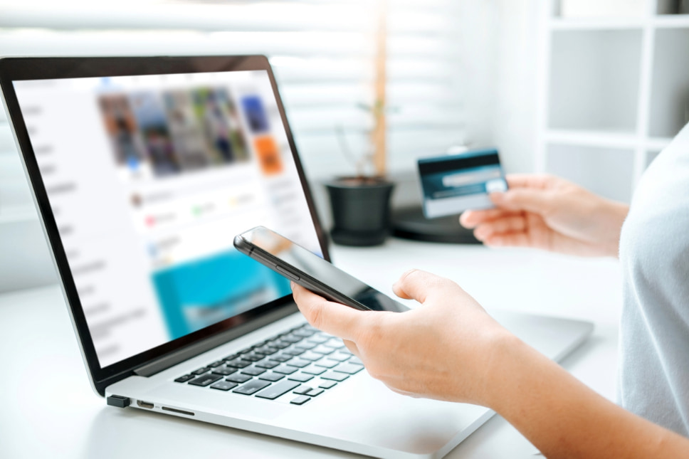 Person holding credit card while shopping online using digital devices, indicating ecommerce success with social media ads