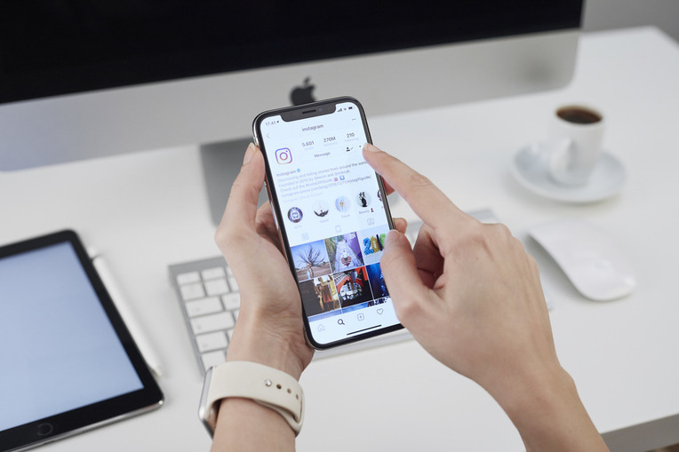 Person at a desk browsing Instagram on a smartphone, signifying business success with social media marketing agency services