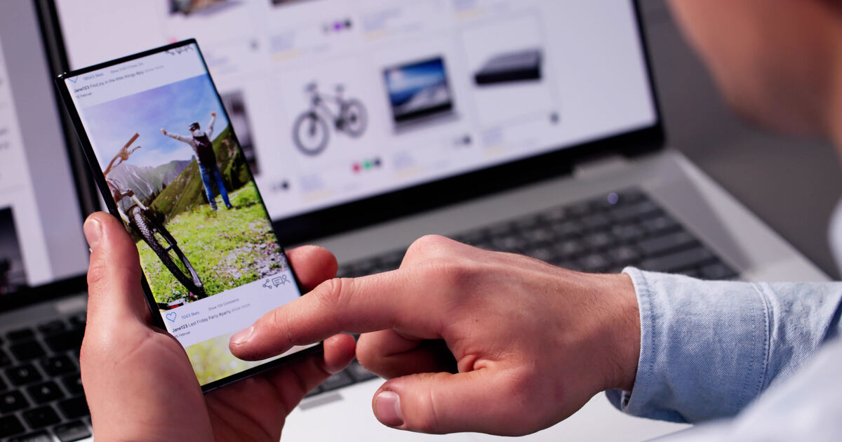 Person using phone and laptop with ecommerce products, illustrating ad retargeting, digital marketing, and online shopping.
