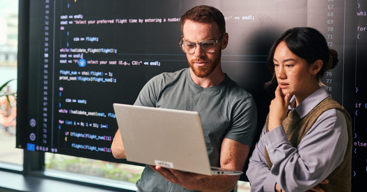 Debunking 7 Common WordPress Security Myths Developers reviewing code on a laptop and large display, illustrating WordPress security, software development, and testing.
