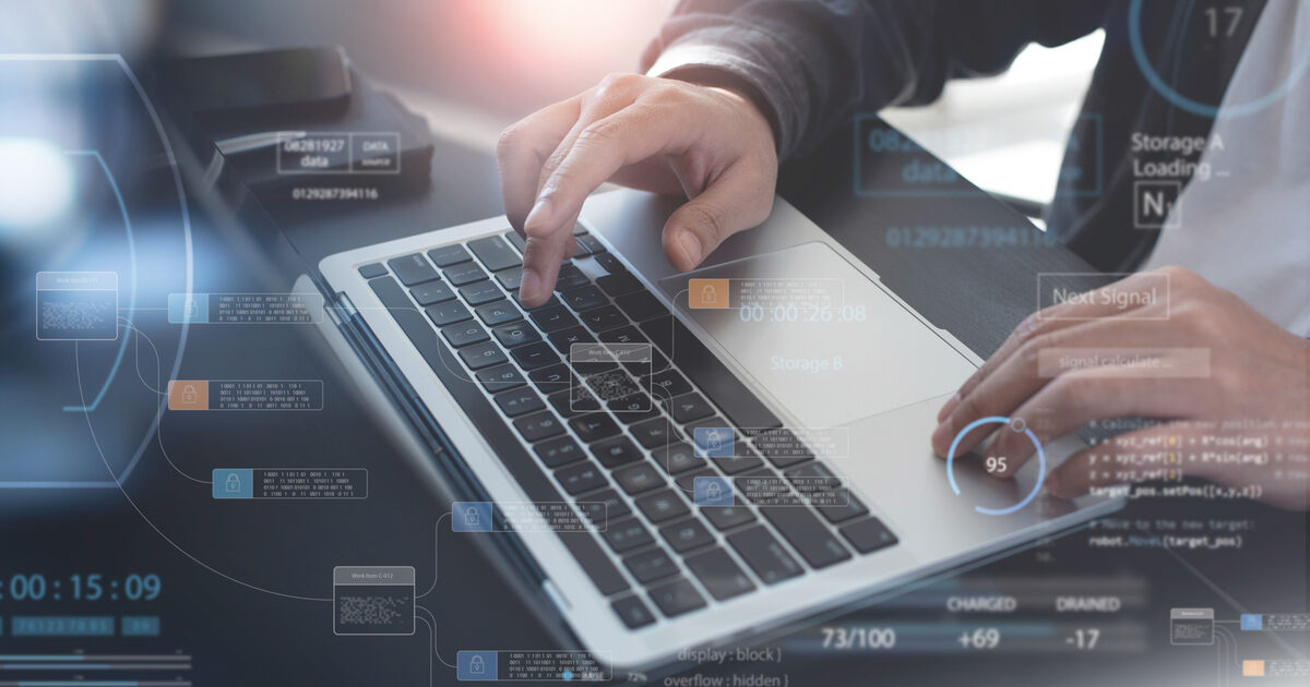 Developer on a laptop with security and automation dashboards, illustrating enterprise web development and digital factories.