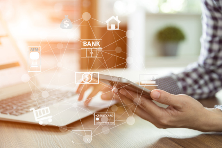 Person using a smartphone with digital banking icons floating above, depicting enhanced online bank visibility on Google Business listings using local PPC ads