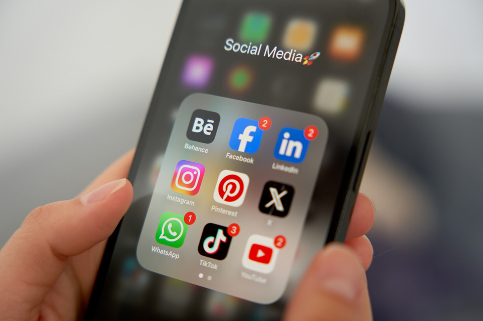 Hand holding a smartphone displaying various social media apps, depicting success with social media advertising services