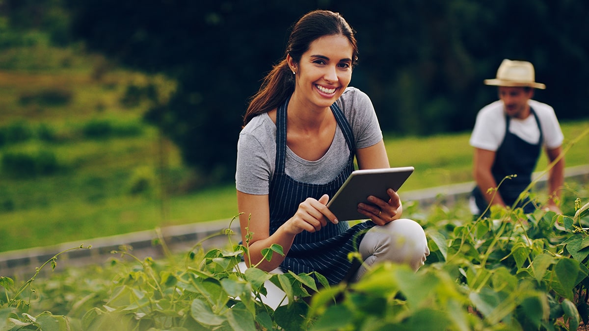 Woman kneeling in field with iPad
