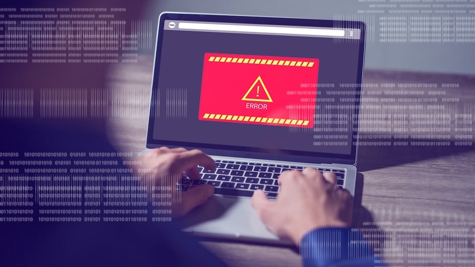 Person using a laptop displaying a prominent error message on the screen with digital binary code in the background, signifying a computer error or alert.