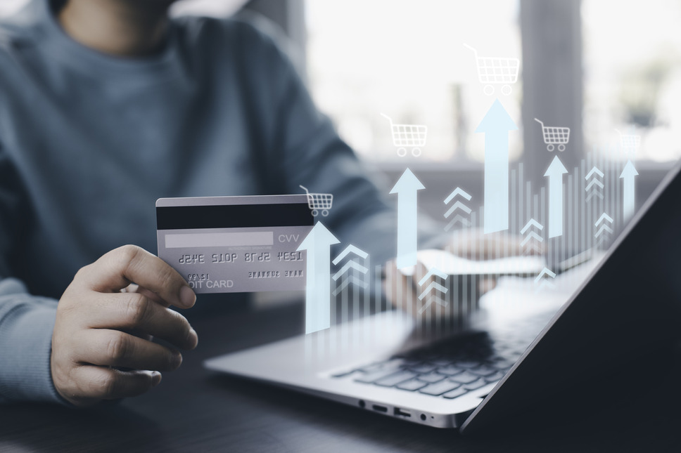 Rising financial graphics with person online shopping using laptop in background, representing increased ecommerce revenue