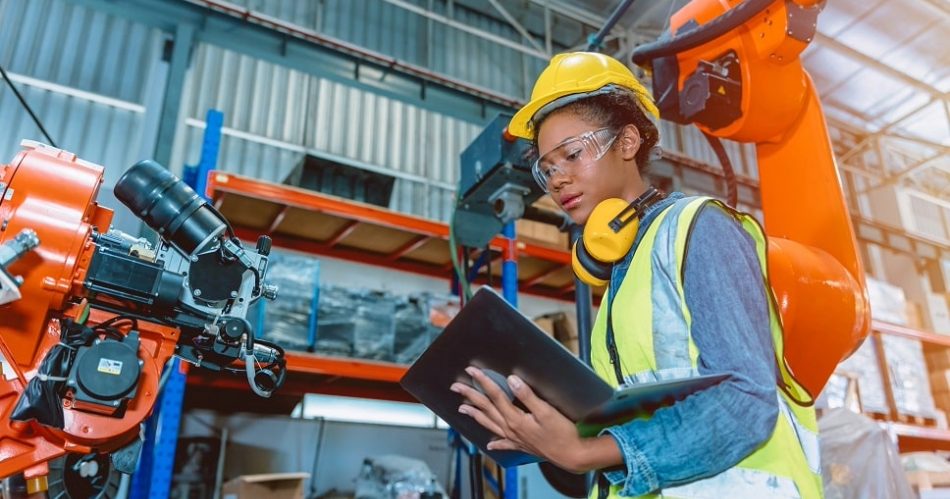 Engineer using a tablet in a manufacturing facility, highlighting industrial technology solutions and manufacturer websites