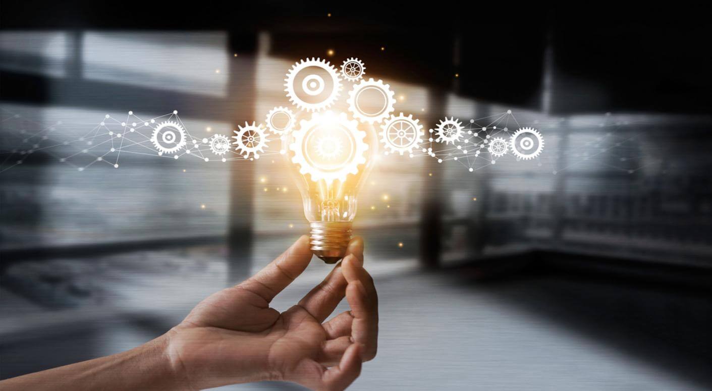 lit lightbulb with gears coming out of it