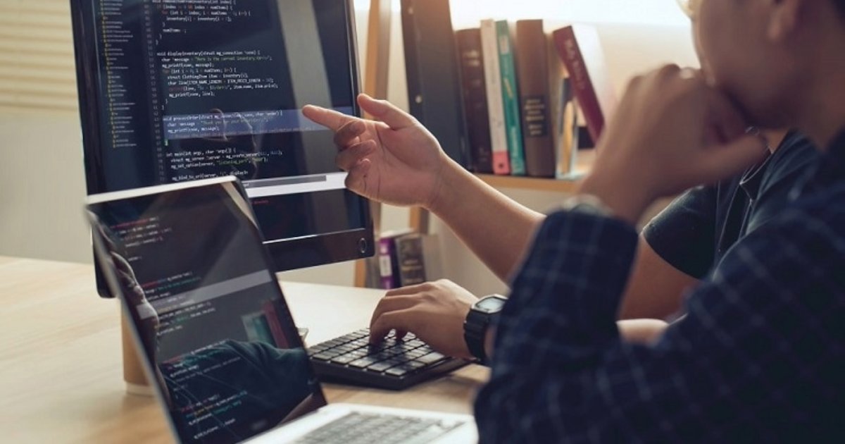 Programmer pointing at code on laptop screen, utilizing Progress Sitefinity CMS features for Sitefinity DX digital experience