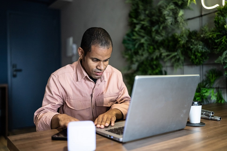 Man working on a laptop, using a screen reader depicting website accessibility