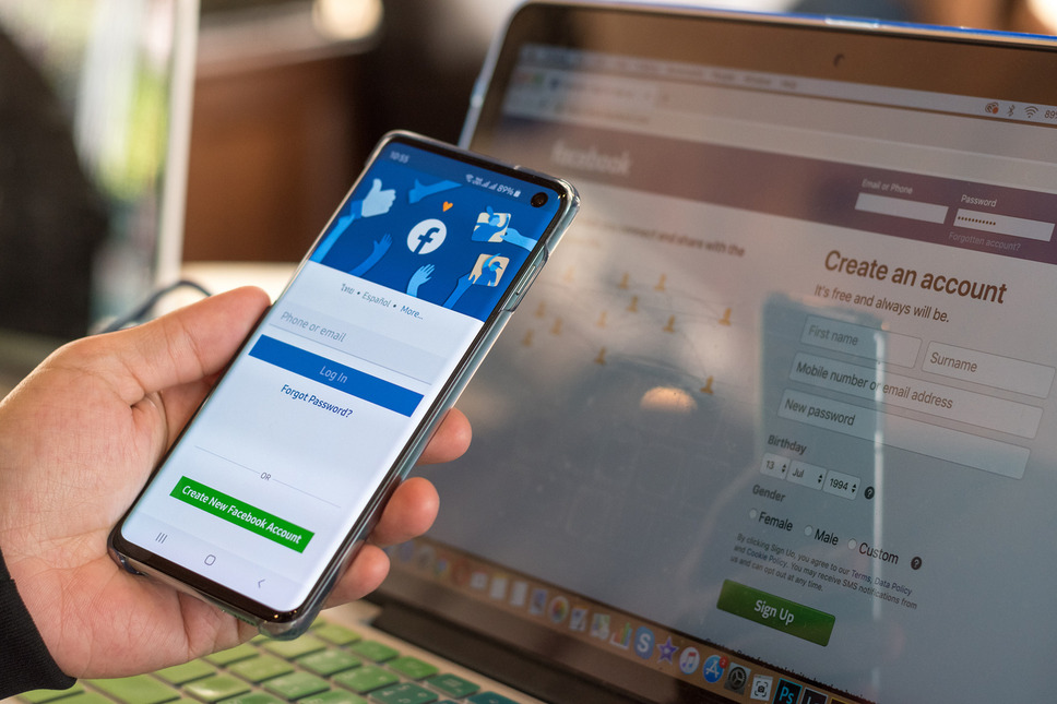 Person using a smartphone and a laptop open in background, representing success with Meta Business Manager account setup
