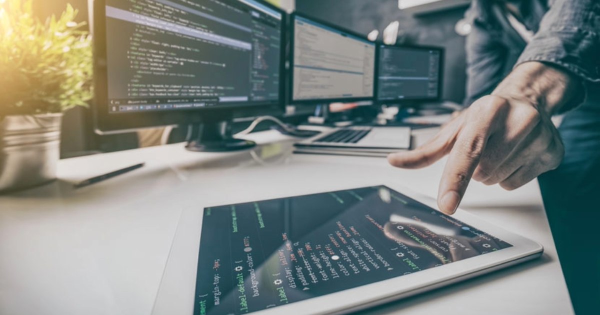 Sitefinity developer working with code on a tablet and multiple monitors displaying text extraction for documents