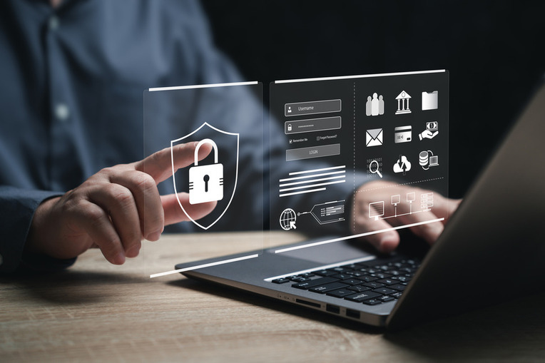 Man at computer reaching towards screen with a digital padlock symbol, representing cybersecurity and data protection on the Sitefinity CMS