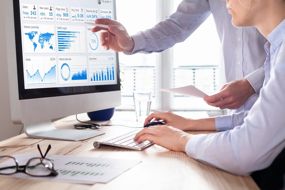 Professionals analyzing data on a computer screen with analytics and graphs displayed."