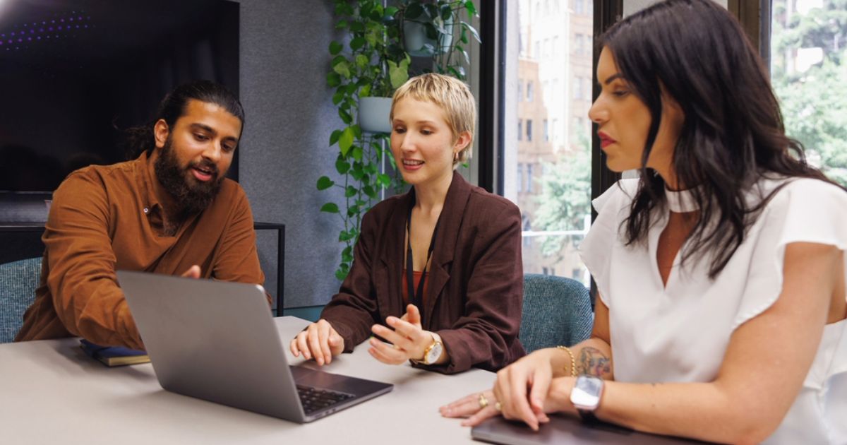 Association learning and marketing team members in an office, reviewing improved performance of member engagement on a laptop