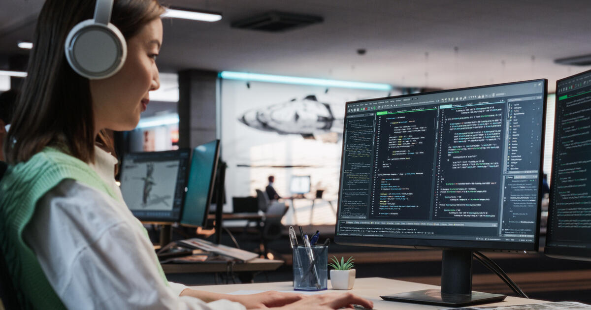 Developer with multiple code editor screens, illustrating full-stack software development and web application programming.