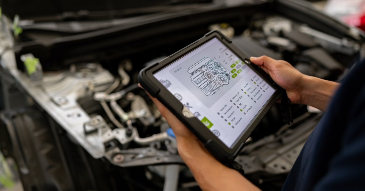 Mechanic using a tablet displaying automotive part details, representing PIES data standards and digital auto part management
