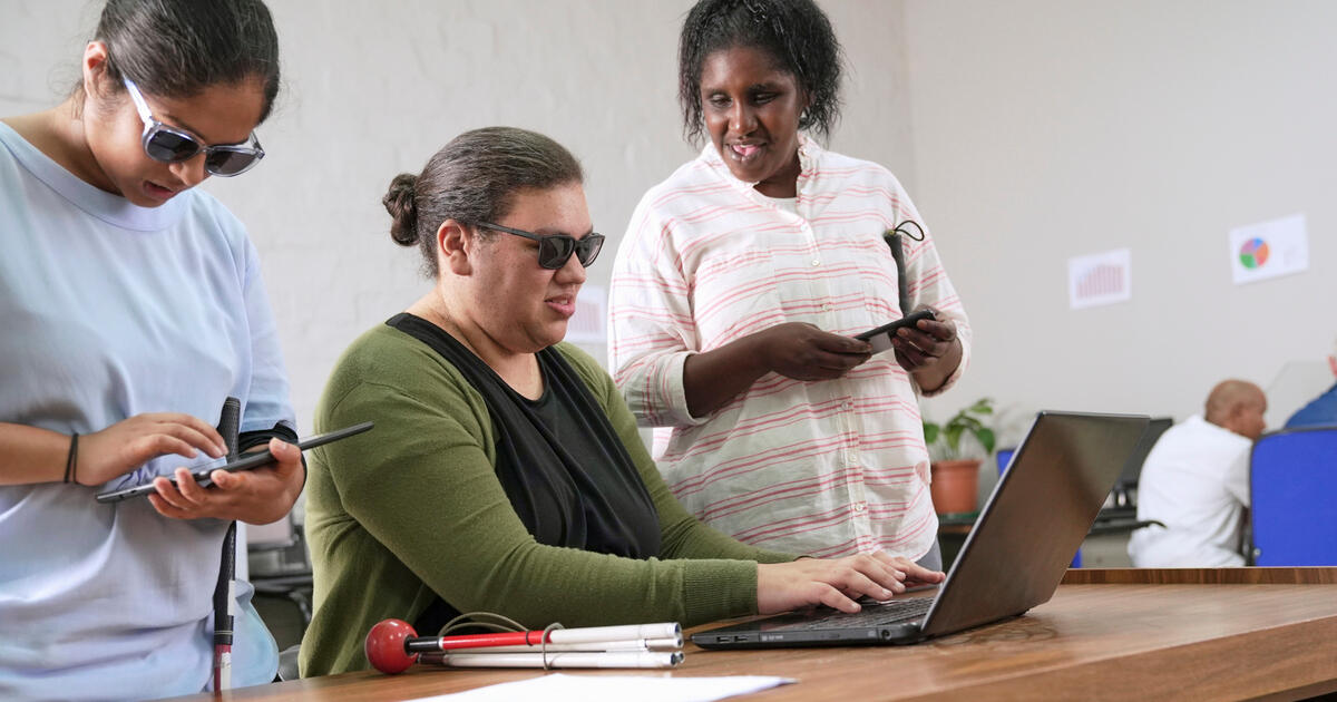 People using assistive technology, including screen readers and a laptop, demonstrating digital accessibility and inclusion.