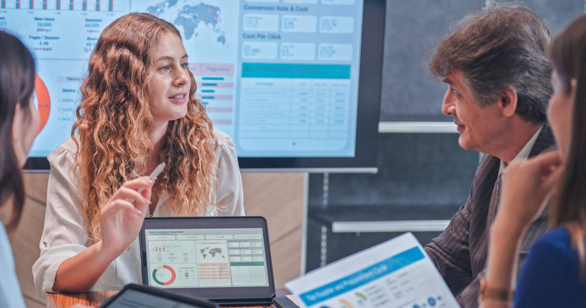 Marketers meeting to review analytics dashboards and campaign reports, highlighting financial marketing attribution and performance insights