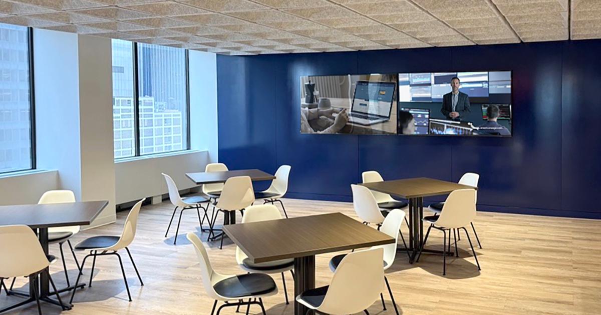 Office break room with tables, chairs, TVs, and windows with city view for Americaneagle.com employees to relax and connect