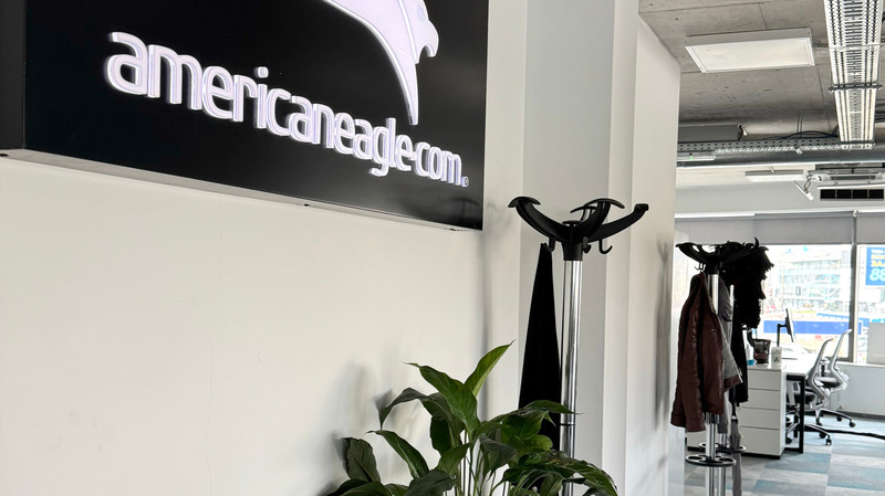 Modern office entrance with Americaneagle.com logo, coat rack, and plants enhancing the welcoming office space in Bulgaria