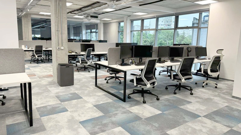 Americaneagle.com modern office space showing grey partitions, ergonomic chairs, and a patterned carpet under natural light