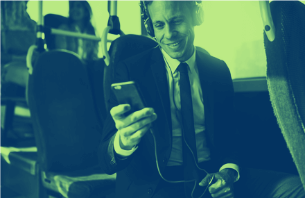 Business person smiling at smartphone while commuting on a bus, signifying success with transit mobile ticketing solutions