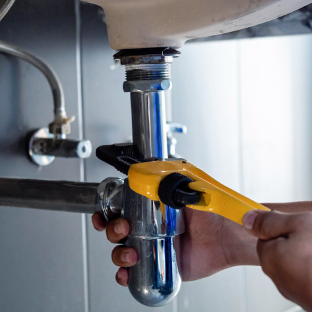 Plumber using wrench to adjust sink pipes, indicating business success with web development and digital marketing services