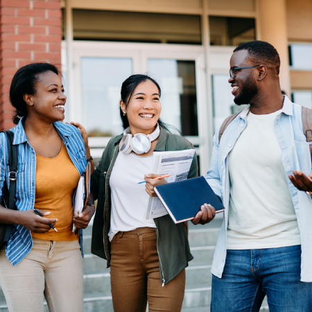 College students interacting outside a campus building, depicting successful digital strategies and services for universities