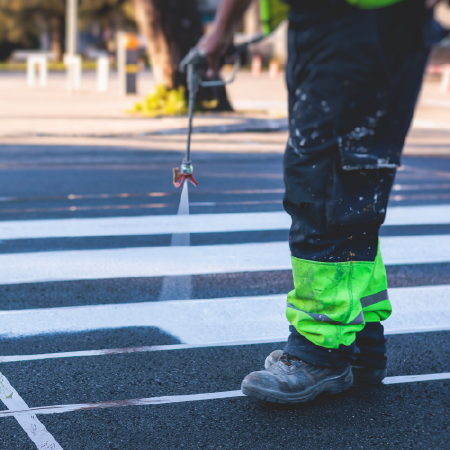 Worker spray-paints crosswalk on road showing business success with digital marketing agency services for transportation