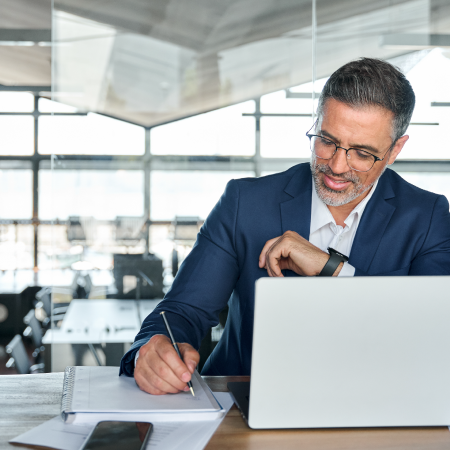 Person writing in a notebook next to a laptop showcasing digital marketing success for financial planning services
