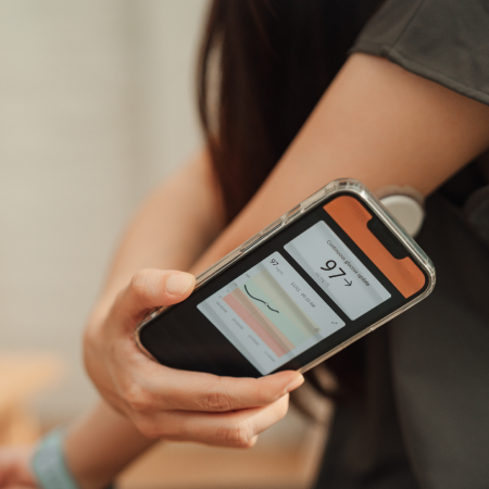 Person viewing glucose levels on a smartphone, showcasing Carelink’s success with digital agency solutions for DME management