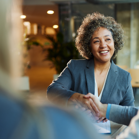 Client smiling and shaking hands across a table, symbolizing business success with digital agency services for banks